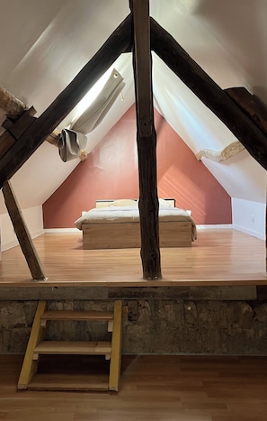 A loft bedroom with a sloped ceiling, wooden beams, a bed, and a ladder. - Pause & vous (Gellainville)