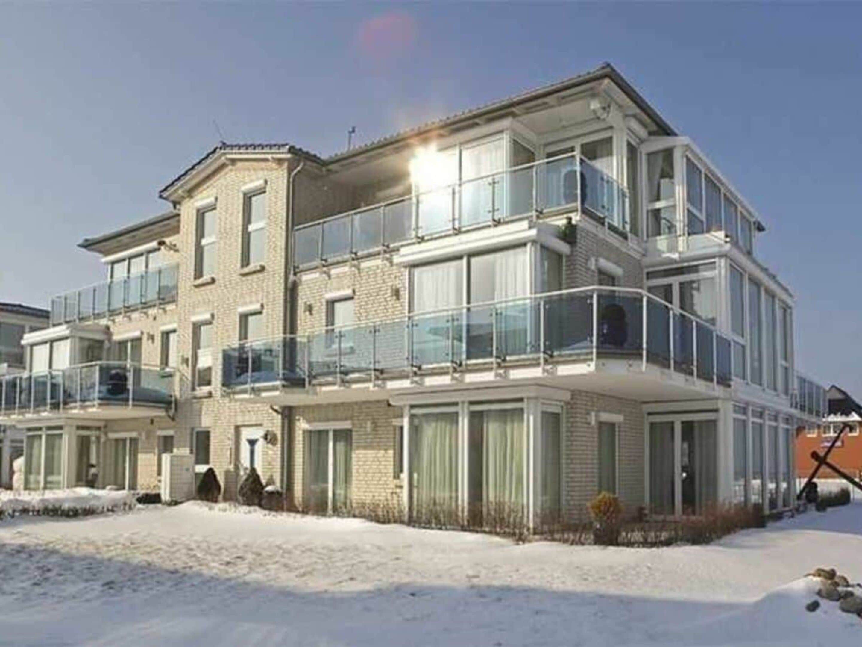 A multi-story residential building with balconies, large windows, and a brick facade.
