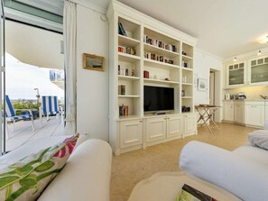 A living room with a TV, bookshelves, a dining area, and a view of the outdoors. - Holiday Apartment 2 \"dorchlauchting\" (Kuehlungsborn)