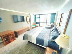 Une chambre à coucher avec un lit, une table de chevet, une lampe et un téléviseur fixé au mur.