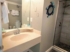 Une salle de bain équipée d’un lavabo, d’un miroir, d’un porte-serviettes et d’une douche.
