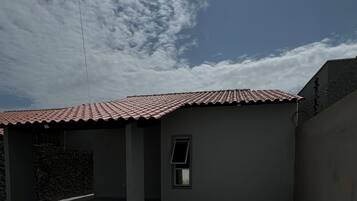 Um pátio com telhado em azulejos, uma pequena janela e piso pavimentado.