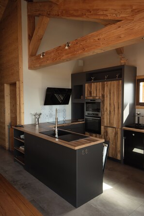 A modern kitchen with a central island, built-in appliances, and exposed wooden beams. - "Serra View" Chalet: Exceptional Views and a Chic, Modern Mountain Atmosphere (Font-Romeu-Odeillo-Via)