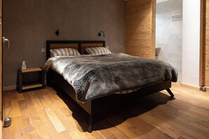 A bedroom with a wooden bed frame, a small bedside table, and a wall-mounted telephone. - "Serra View" Chalet: Exceptional Views and a Chic, Modern Mountain Atmosphere (Font-Romeu-Odeillo-Via)