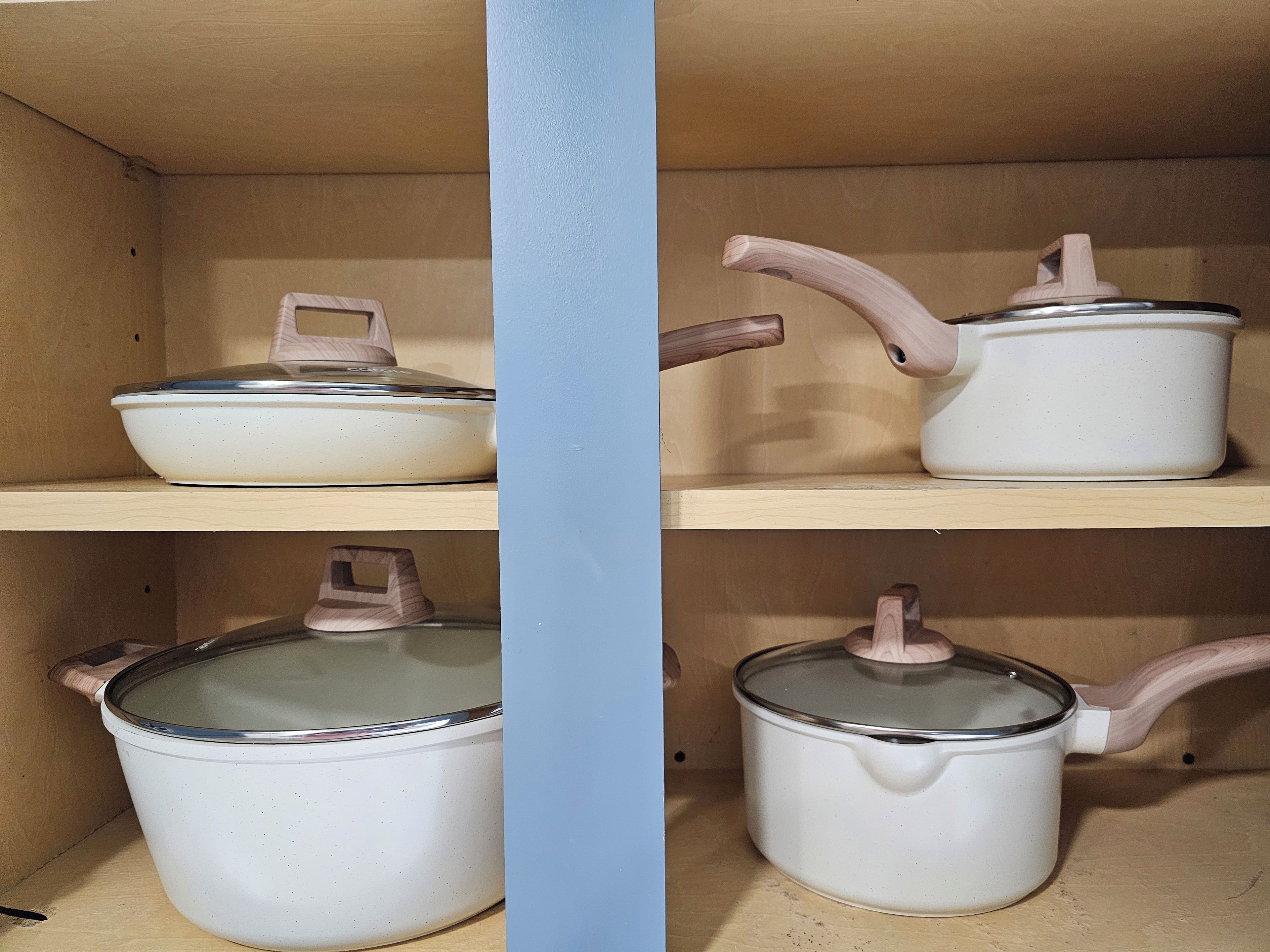 Une étagère de cuisine avec trois pots blancs dotés de couvercles et d’une anse en bois chacun.