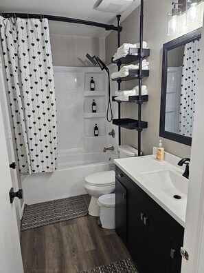 A bathroom with a bathtub, toilet, and a sink with a mirror. - 6 Beds Ideal for Crews & Insurance I Close to Naval Base and 6 flags (Waukegan)