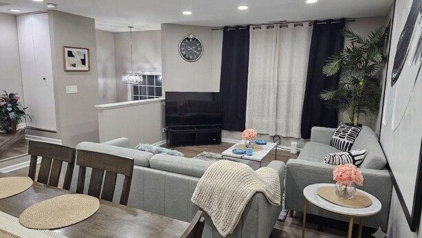 A modern living room with a sofa set, a dining table with placemats, a coffee table, and a television. - 6 Beds Ideal for Crews & Insurance I Close to Naval Base and 6 flags (Waukegan)