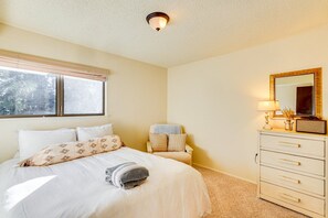 Ein Schlafzimmer mit Bett, Nachttisch, Kommode, Fenster und Deckenleuchte.
