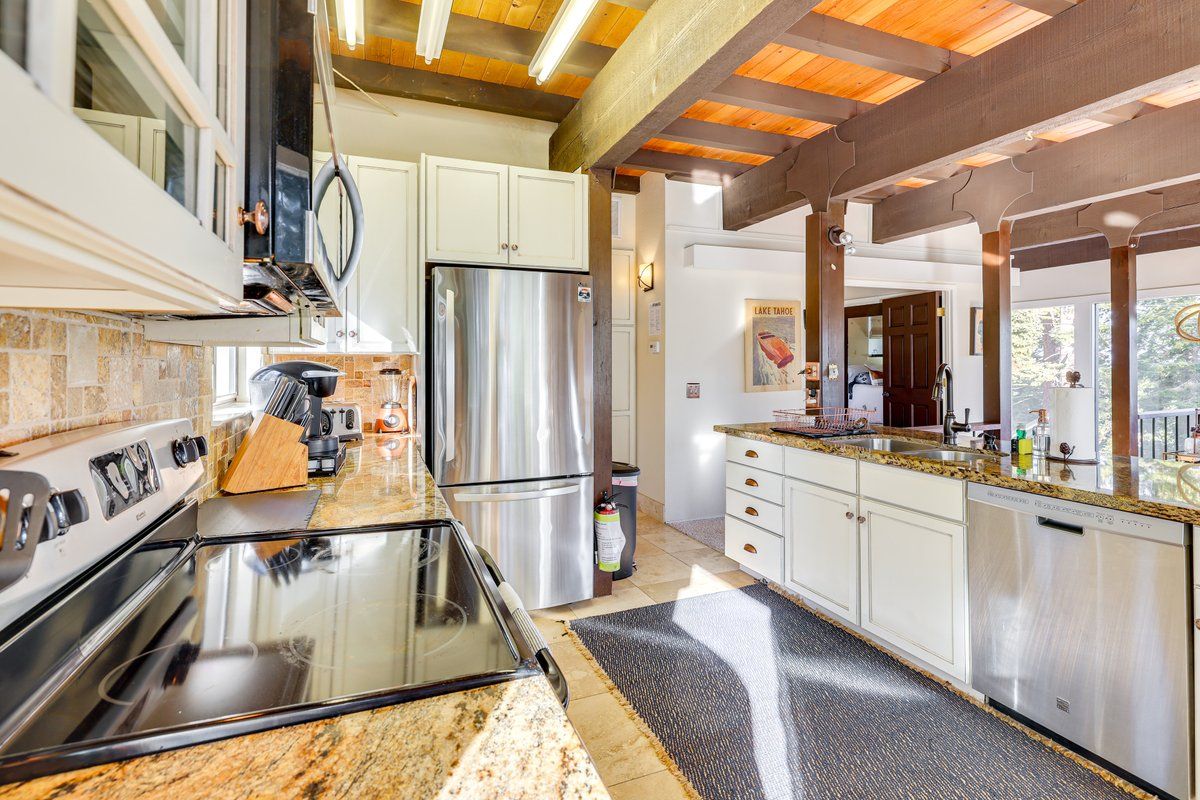 Una cocina moderna con encimeras de granito, electrodomésticos de acero inoxidable y techo de madera.
