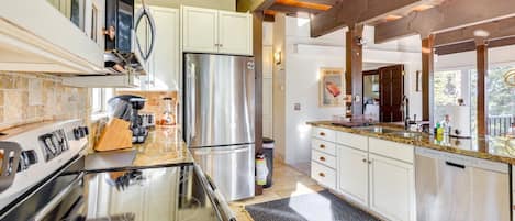 Una cocina moderna con encimeras de granito, electrodomésticos de acero inoxidable y techo de madera.