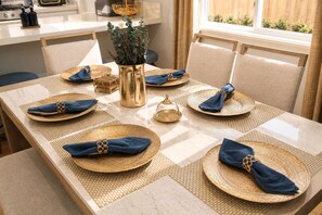 A dining table set with gold-rimmed plates, blue napkins, and a decorative vase. - Lux Pacific Beach - Rooftop Terrace, Walk to Sand (San Diego)