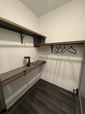 A walk-in closet with wooden shelves, a shoe rack, and hanging clothes. - The Luxury Den Just Mins from Downtown Houston (Houston)