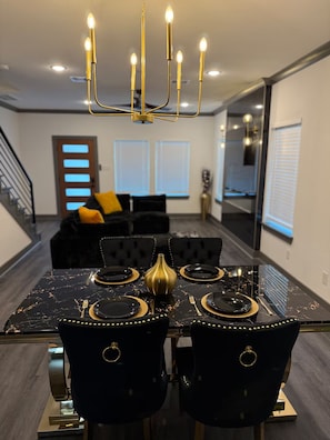 A dining area with a black marble table, gold accents, and black upholstered chairs. - The Luxury Den Just Mins from Downtown Houston (Houston)