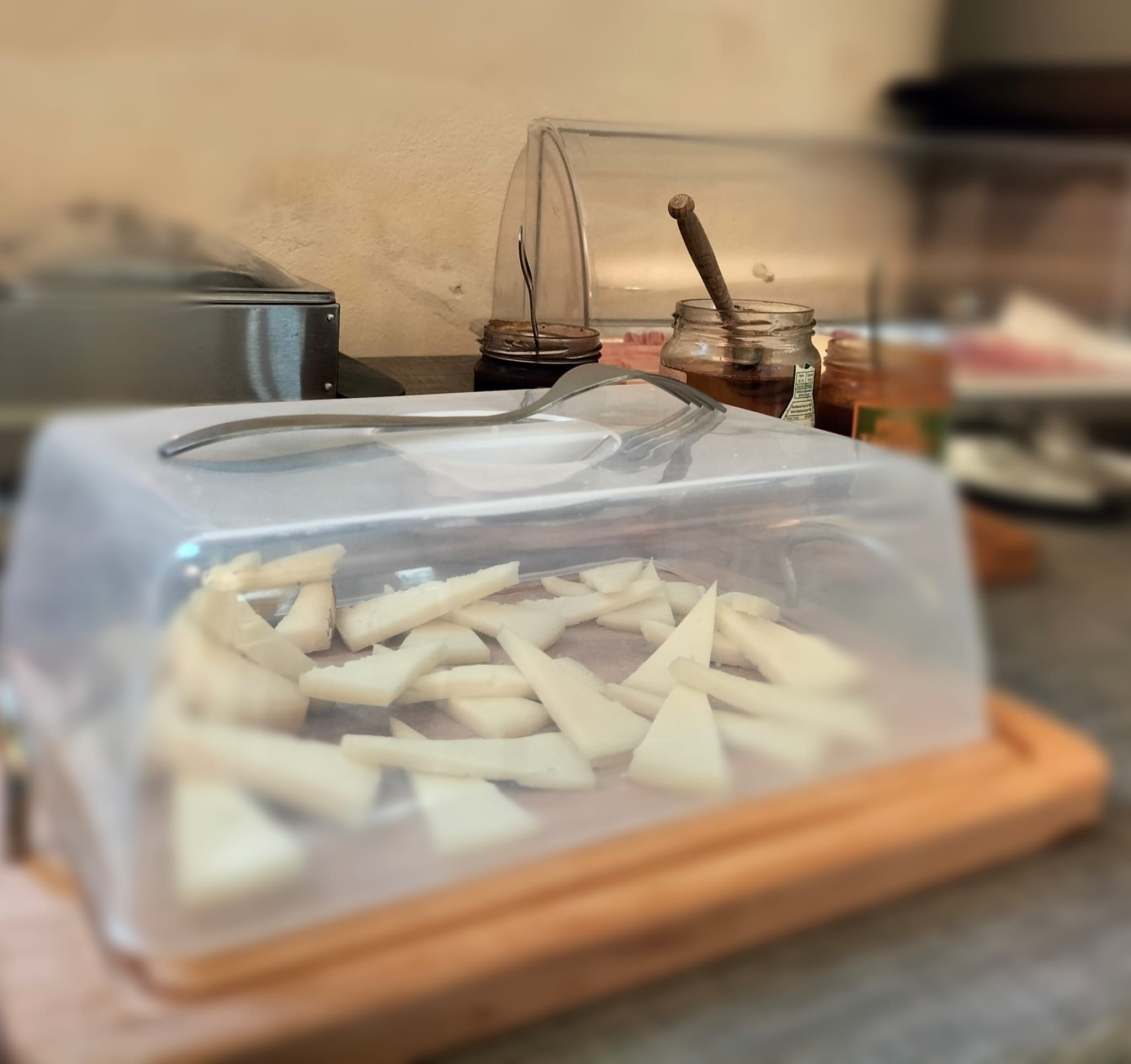 Un contenitore per alimenti con coperchio trasparente, posato su un tagliere di legno.