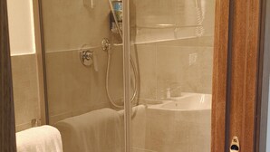 A glass-enclosed shower area with a towel rack and a visible bathroom sink.