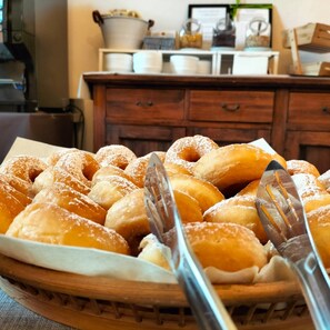 A wooden tray filled with doughnuts dusted with powdered sugar, accompanied by a fork and a knife. - Just a stone's throw from Volterra: rooms with all the comforts (Volterra)