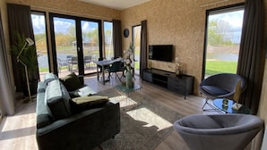 Una sala de estar moderna con un sofá, un televisor y un comedor con sillas y una mesa.