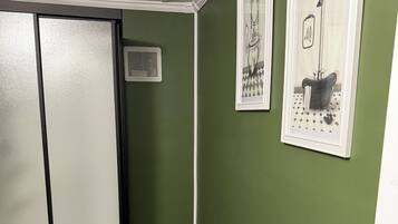 Um banheiro com vaso sanitário, lixeira e quadros nas paredes.