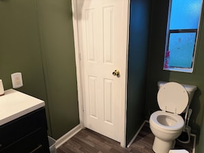 A bathroom with a white toilet, a white sink, and a door with a brass doorknob.