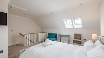 Een slaapkamer met een bed, een bureau, een stoel, een televisie en een raam.