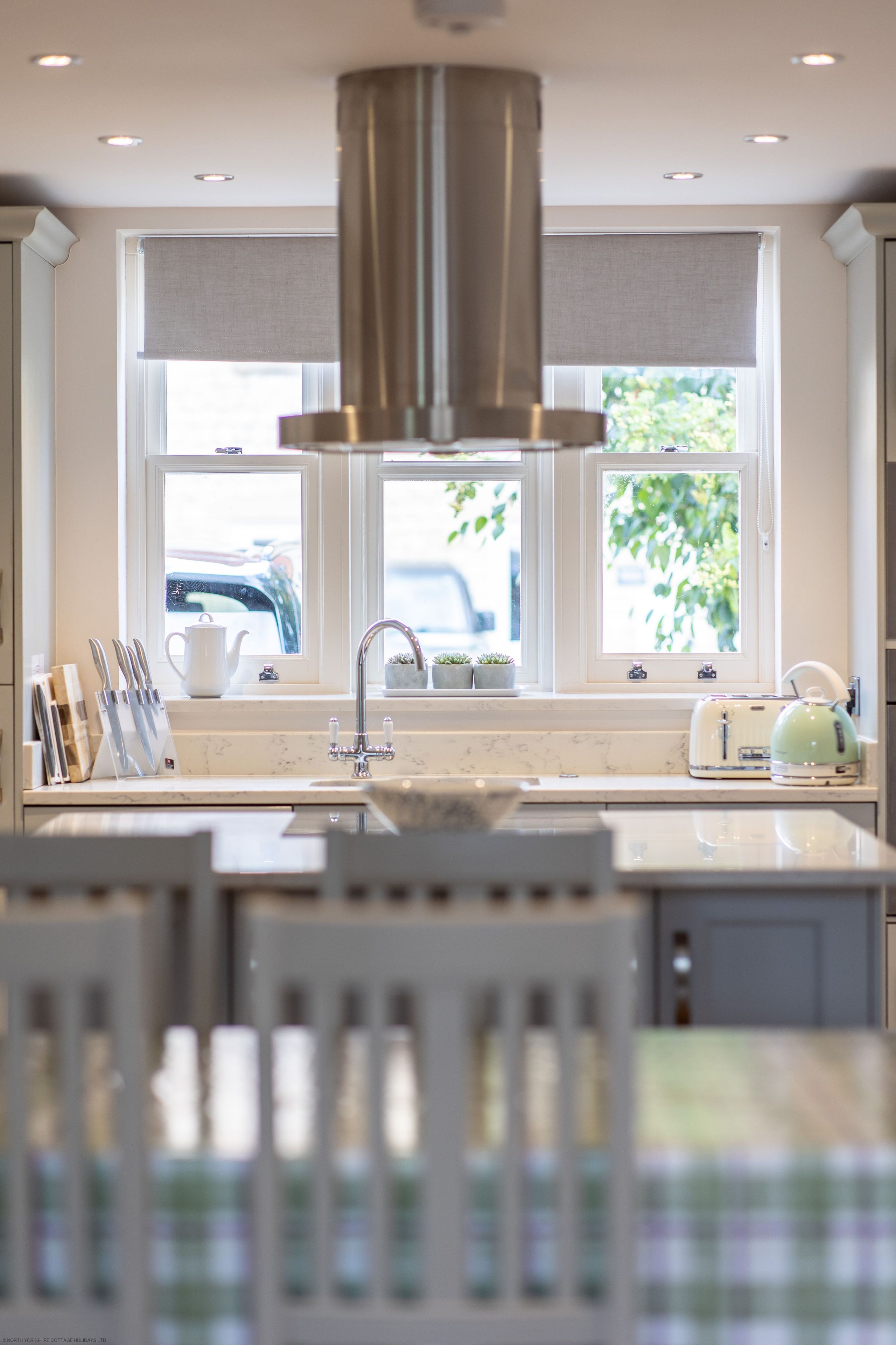 A kitchen with a central island, a sink, and a window with a view of the outside.