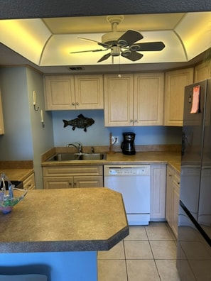 A kitchen with a dishwasher, refrigerator, and a ceiling fan. - Cozy Ocean & Pool View 2-Bedroom, 2-Bathroom Condo in Amazing Ormond Beach Fla. (Ormond Beach)