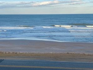 A beach with waves and a road in the foreground. - Cozy Ocean & Pool View 2-Bedroom, 2-Bathroom Condo in Amazing Ormond Beach Fla. (Ormond Beach)