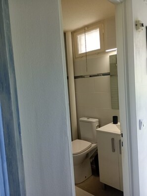 Ein kleines, kompaktes Badezimmer mit Toilette, Waschbecken und Spiegel.