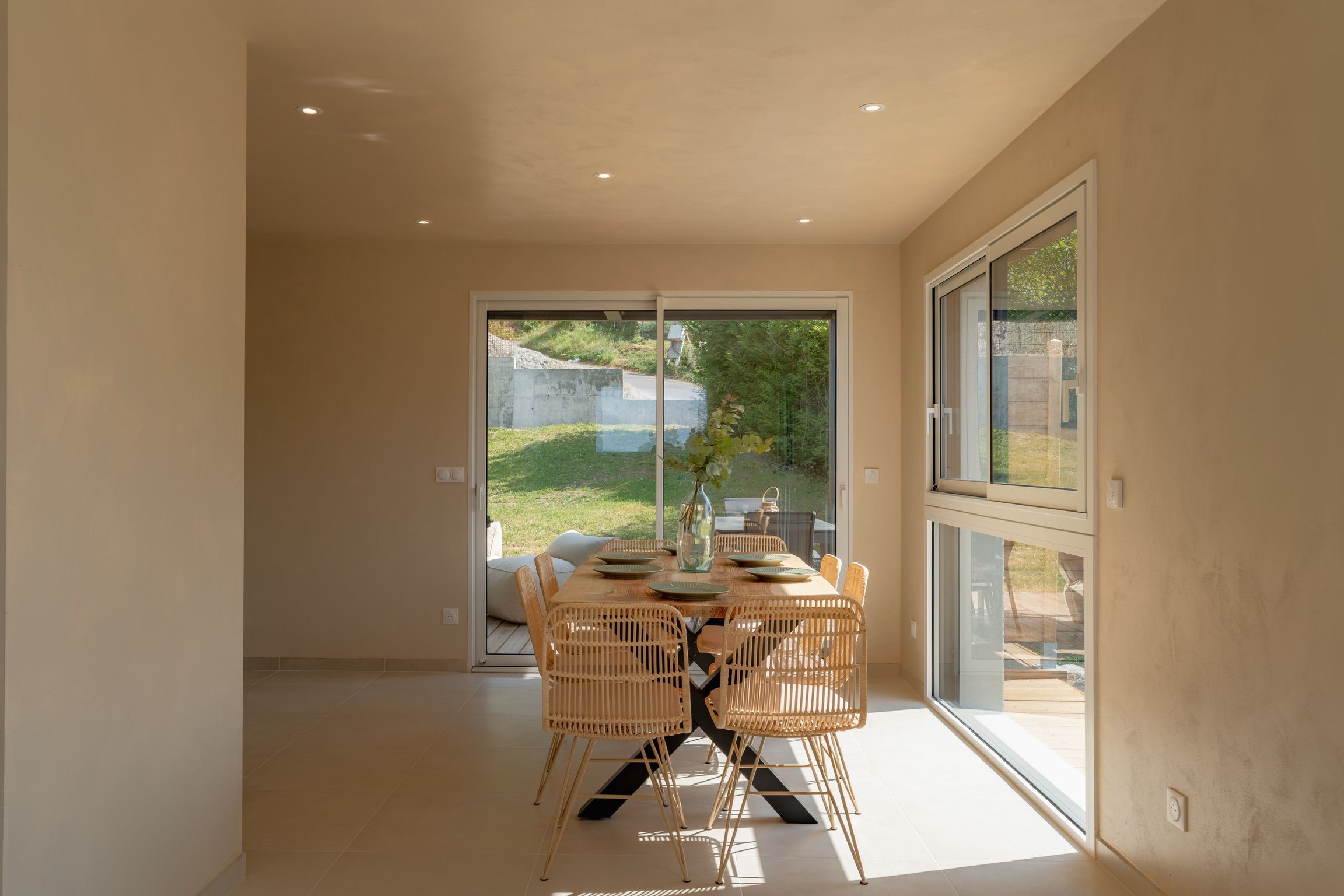 Un espace repas moderne avec une porte vitrée donnant sur un jardin.