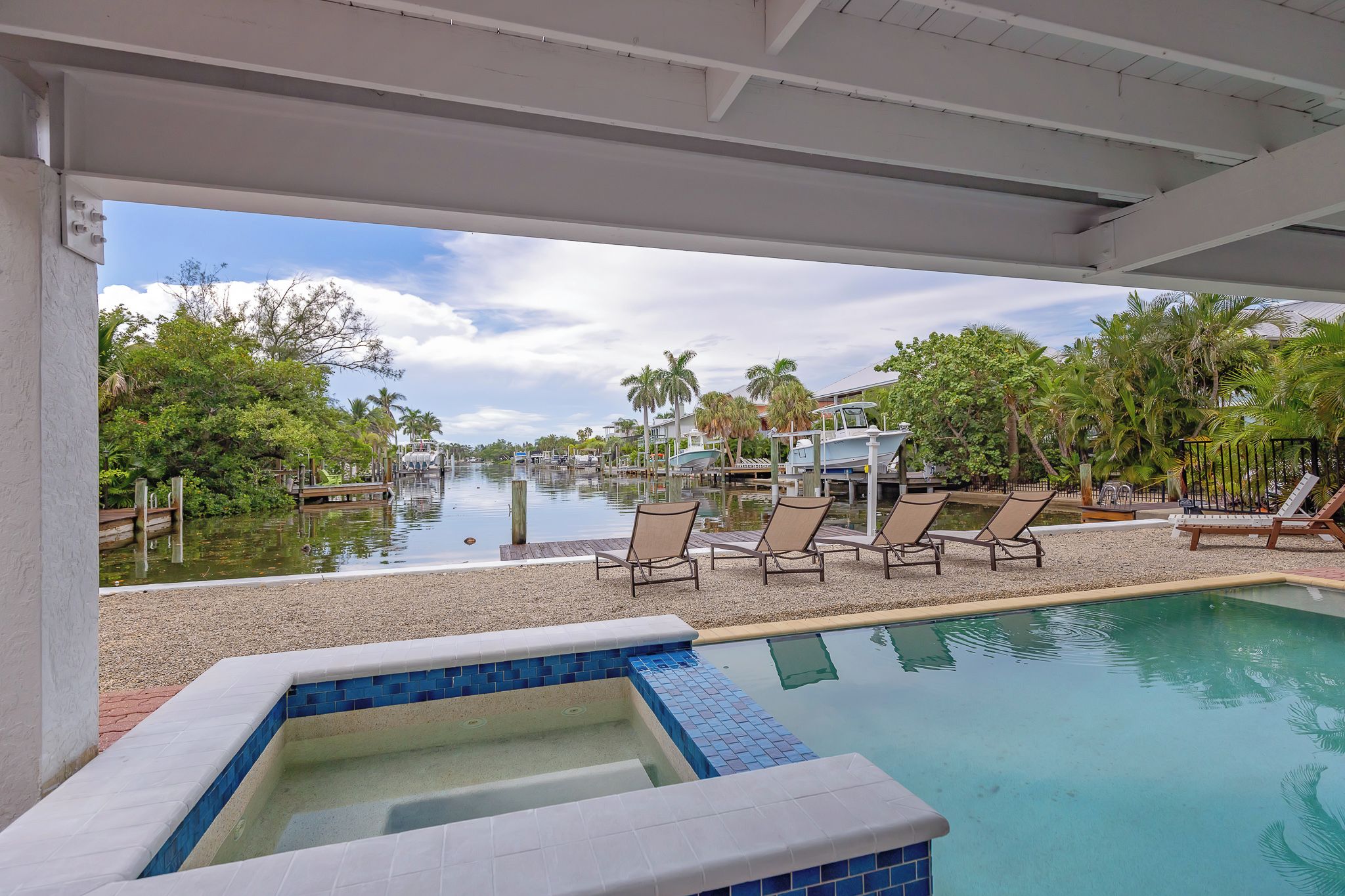 A pool area with lounge chairs and a view of a marina with boats.