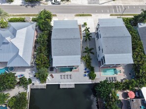 A residential area with two buildings, a swimming pool, and a dock extending into a body of water. - Sea Swept Mermaid: Canal-front with pool and kayaks (Anna Maria)