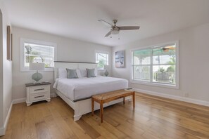 A bedroom with a bed, bedside tables, a bench, and large windows. - Sea Swept Mermaid: Canal-front with pool and kayaks (Anna Maria)