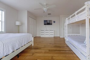 A bedroom with a bunk bed, a desk with drawers, a ceiling fan, and a television on the wall. - Sea Swept Mermaid: Canal-front with pool and kayaks (Anna Maria)