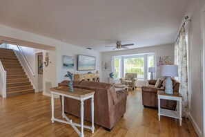 A spacious living room with a staircase, wooden flooring, and a ceiling fan. - Sea Swept Mermaid: Canal-front with pool and kayaks (Anna Maria)