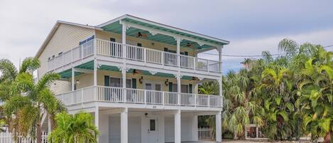 A two-story building with a balcony on each floor, surrounded by palm trees.