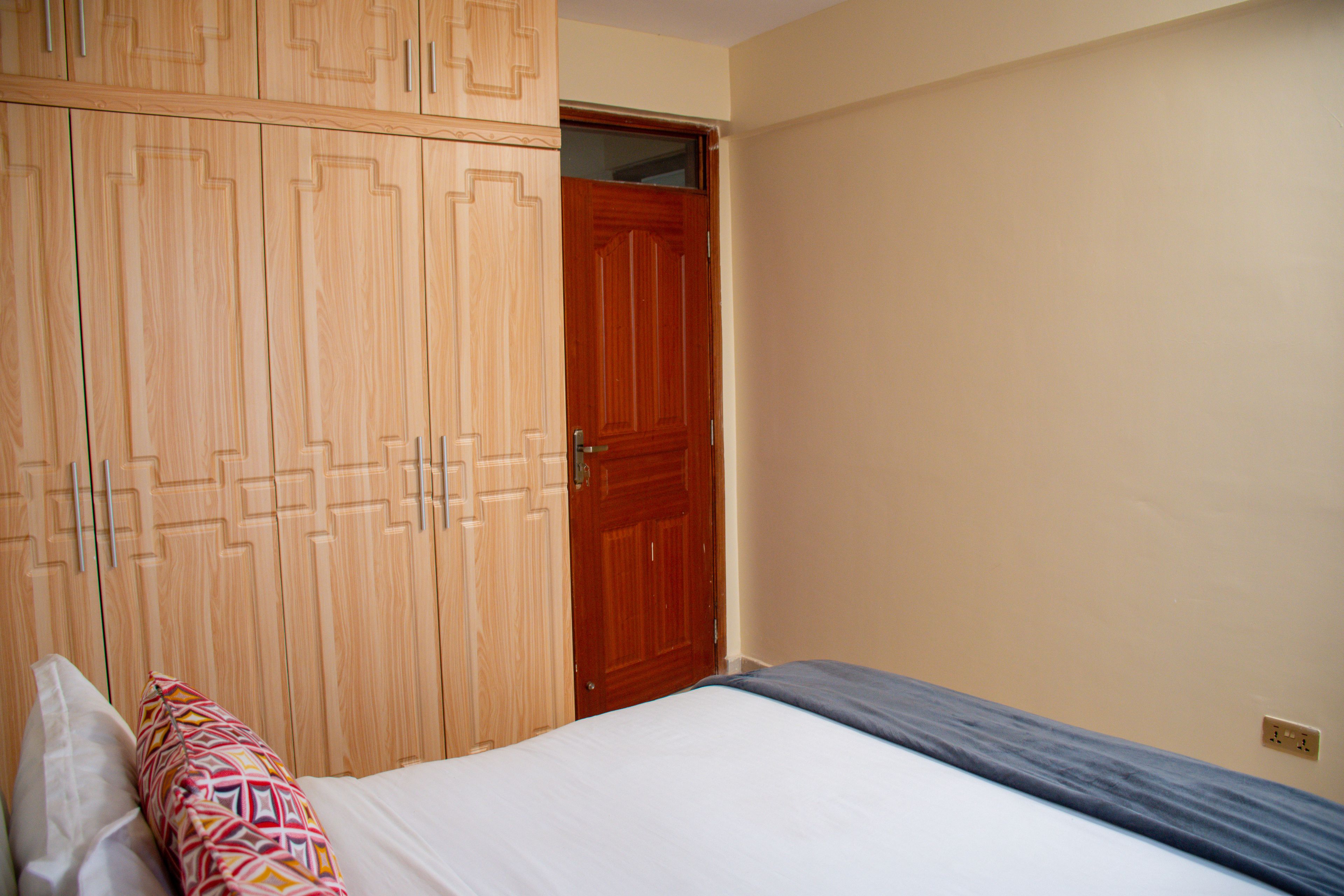 Een slaapkamer met een bed, een kledingkast en een deur.