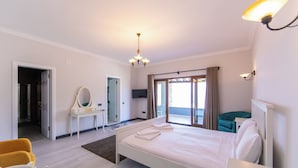 A hotel room with a bed, a desk, a chair, a mirror, a television, and a view of the outdoors. - Mira villa 1 (Torba)
