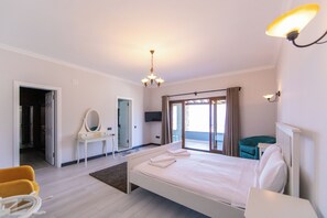 A hotel room with a bed, a desk, a chair, a mirror, a television, and a view of the outdoors. - Mira villa 1 (Torba)