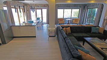 Amplia sala de estar con sofá, mesa de comedor y área de cocina con armarios y refrigerador.