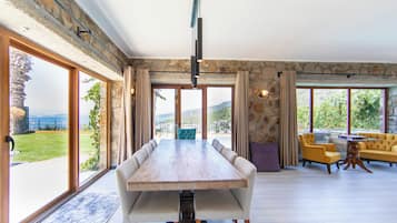 Un comedor amplio con una gran mesa de madera, varias sillas y vistas al exterior a través de amplios ventanales.
