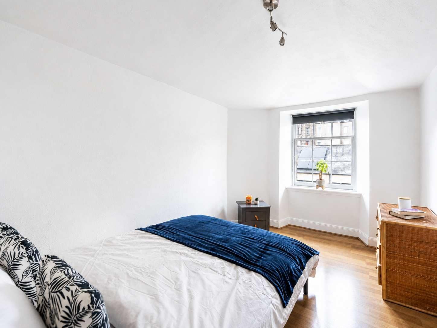 A bedroom with a bed, a nightstand, a window, and a dresser.