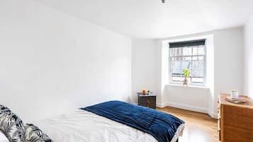 A bedroom with a bed, a nightstand, a window, and a dresser.