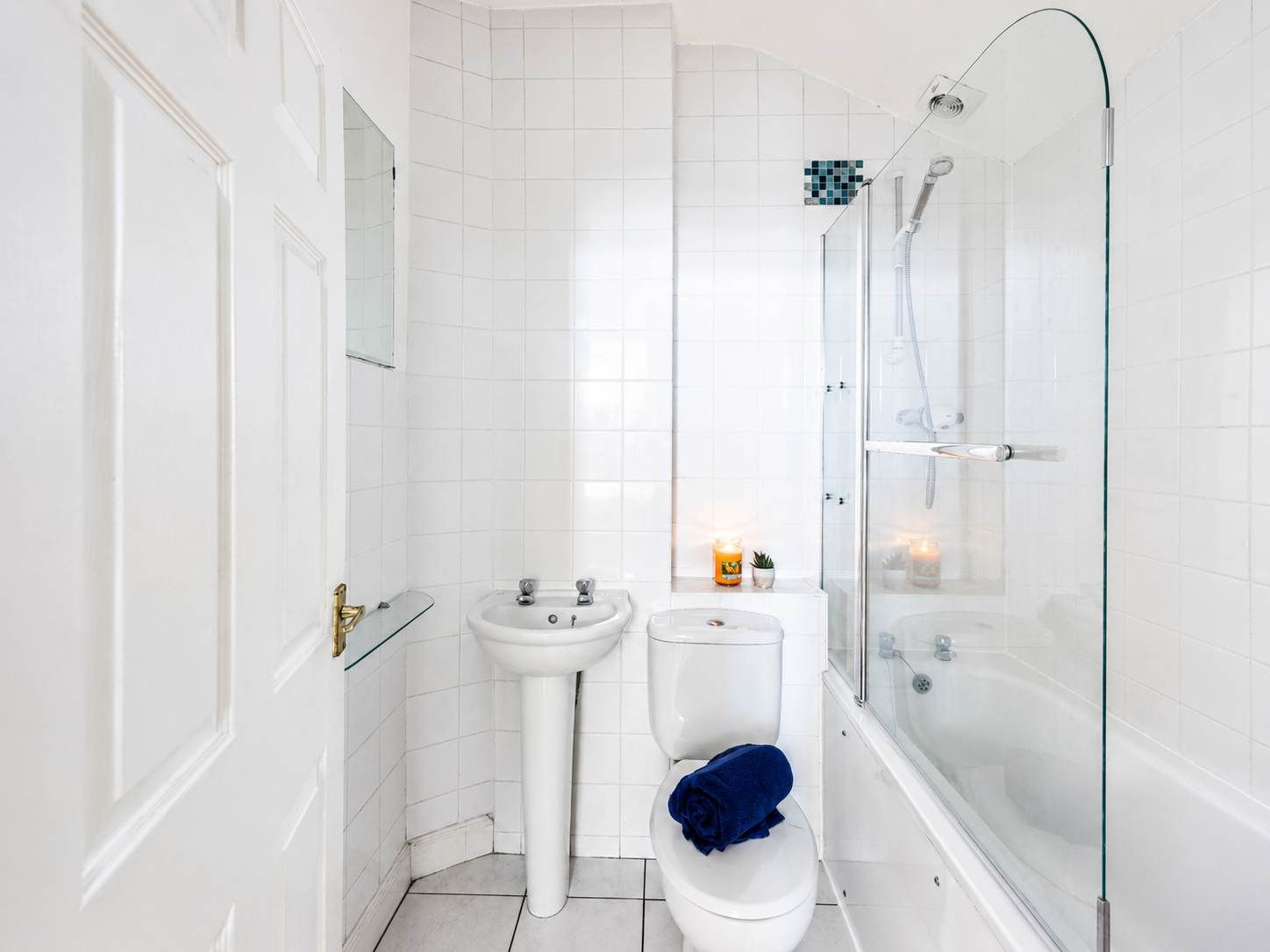 A bathroom with a glass-enclosed shower, a white sink, and a toilet.