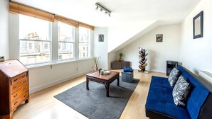 En stue med sofa, sofabord, kommode og pejs.