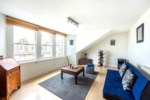 A living room with a sofa, a coffee table, a dresser, and a fireplace. - Cozy 1BR in New Town - Steps from the Royal Mile (Edinburgh)