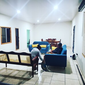 Een woonkamer met een bank, een eettafel met stoelen en een lange bank.