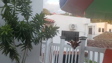 Een houten terras met een bloempot, een wit hek en een kleurrijke parasol.