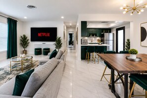 A modern living room with a sofa, a coffee table, and a TV mounted on the wall. - NEW! Modern Coastal 5BR, Sunset Villa Near Beach (Pompano Beach)