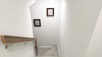 A staircase with a wooden handrail and a carpeted landing.
