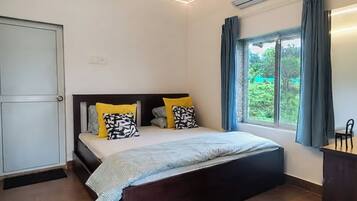 A bedroom with a bed, a bedside table, a window with curtains, and a door.